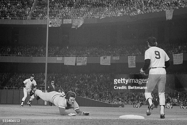 Reds' Pete Rose pulls one of his patented diving slides into third base, advancing from first on Ken Criffey's single in the 8th inning. Yankee third...
