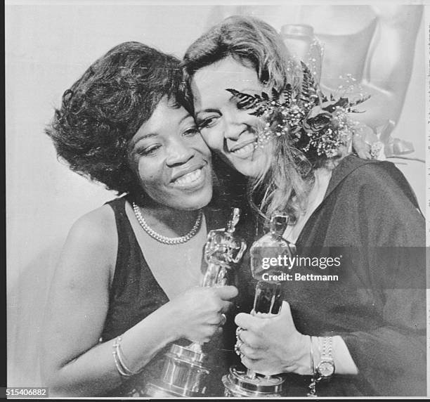 Aletha Finch, widow of late actor Peter Finch, hugs actress Faye Dunaway after accepting her husband's Oscar for him at the 49th Annual Academy...