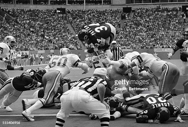 Chicago Bears' Walter Payton goes over the top of Dallas Cowboys Thomas Henderson to score a touchdown on a third and one play that narrowed the...