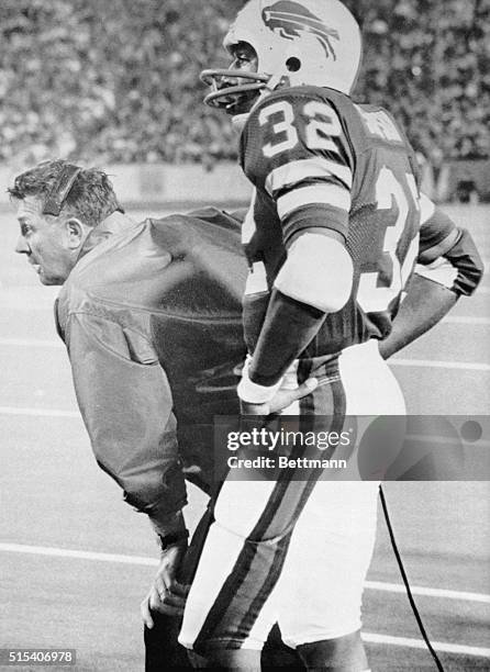 Simpson and Buffalo coach, Lou Saban, watch the play in the first quarter. At half time Miami leads, 17-14, over Buffalo.