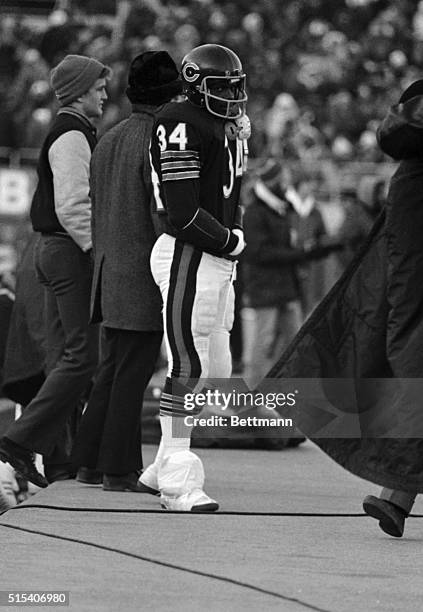 Chicago Bears' disappointed running back Walter Payton stands on sideline, his injured right ankle wrapped in a bubble-like bandage containing ice...