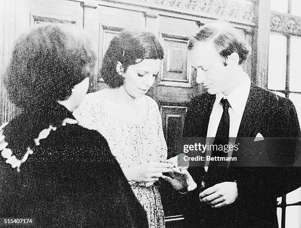 Heiress Christina Onassis places the wedding ring on the finger of Sergei Kauzov at wedding ceremony here August 1. His mother watches at left.