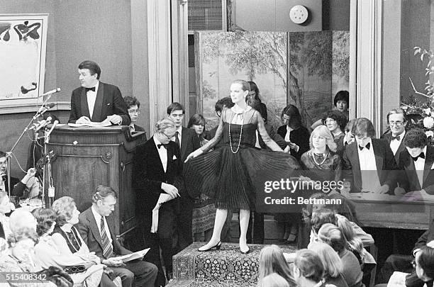 Coco Chanel's famous "little black dress," a short evening dress of black pleated silk chiffon with bootlace straps and a gauze jacket, being shown...