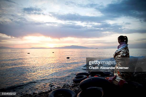 Small Syrian girl looks on during sunrise after arriving on an inflatable boat with other refugees, crossing the sea from Turkey to Lesbos, some 5...