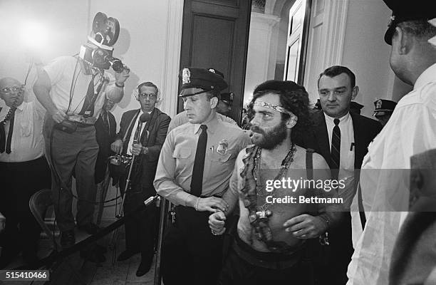 Washington, D.C.- Jerry Rubin, a leader of the Youth International Party, , is escorted from a hearing of the House Un-American Activities...