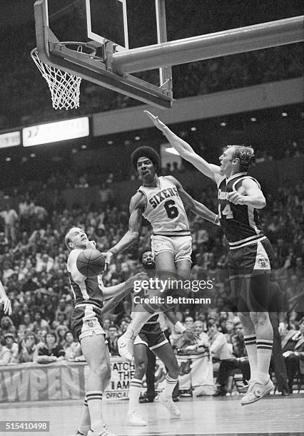 Sixers' Julius Erving passes the ball off between Denver Nuggets' Dan Issel and Phil Ricks in the second quarter of action at the Spectrum in...