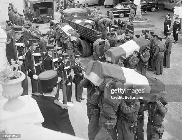 Algiers, Algeria- As soldiers at left salute with their weapons, other troops carry flag-draped coffins during a funeral service for slain gendarmes...