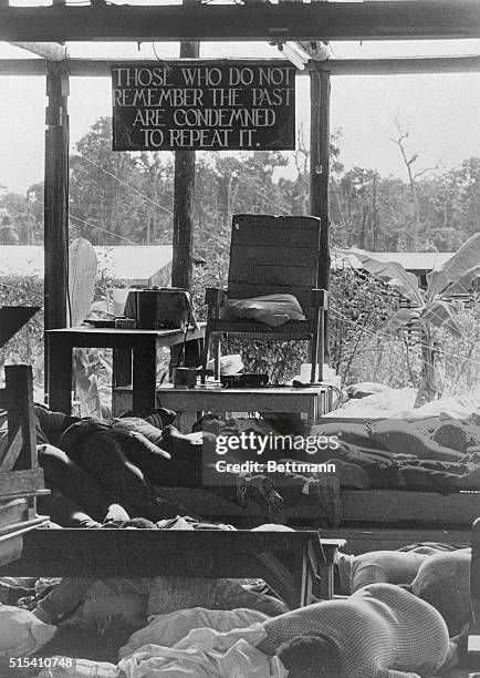 Bodies of cultists lie around the "throne" used by Jim Jones in his meeting hall here. The sign above states that "Those who do not remember the past...