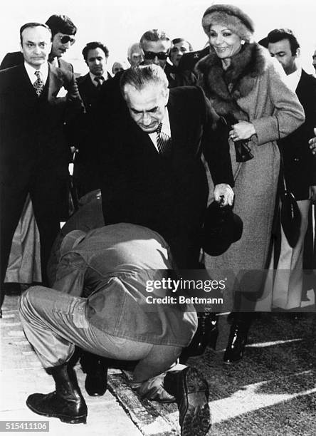 Tehran, Iran- An Iranian soldier kisses the feet of Shah Mohammed Riza Pahlevi as other aides of the Monarch look on grimly and Empress Farah looks...