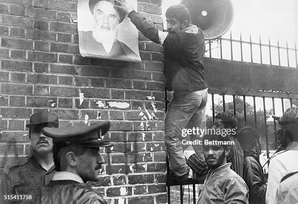 Tehran, Iran- A Moslem revolutionary puts up a poster of Ayatollah Khomeini on the outer wall of the U.S. Embassy compound, occupied 11/4 by students...