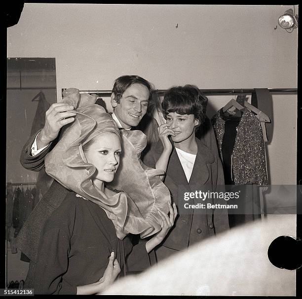 Paris, France-French couturier Pierre Cardin , and a model show an extravagant hat to his friend, actress Jeanne Moreau , after Cardin's presentation...