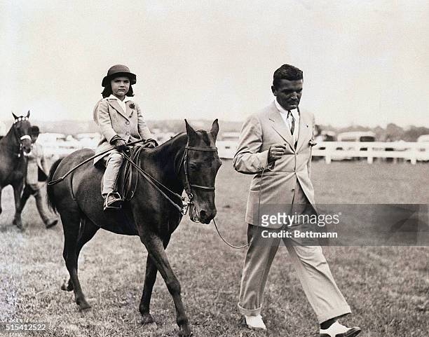 Young Jacqueline Bouvier rides horseback as her dad, John, walks at her side. | Location: Probabally East Hampton, New York, USA.
