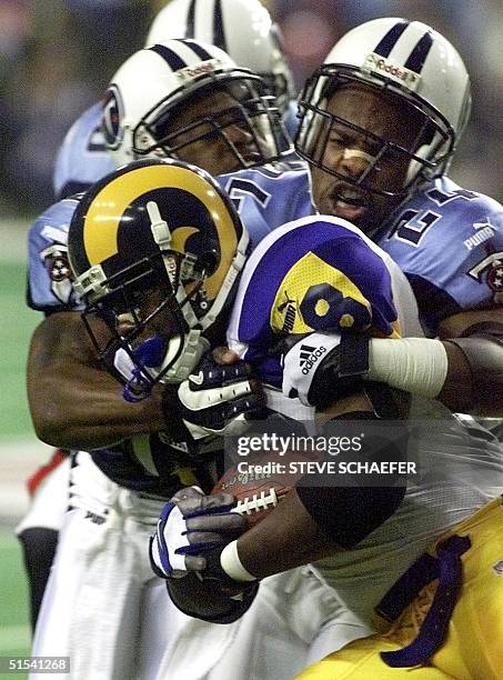 St. Louis Rams running back Marshall Faulk is wrapped up by Tennessee Titans safety Steve Jackson during first half action in Super Bowl XXXIV at the...