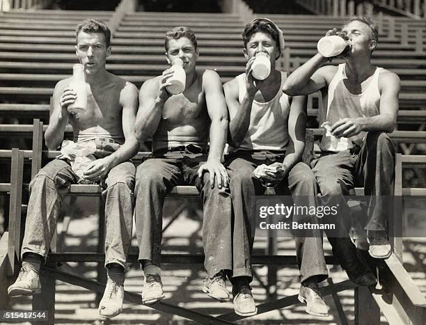 Four Boston College football players drink bottles of milk during a break in the construction of the University's new stadium, which they're helping...