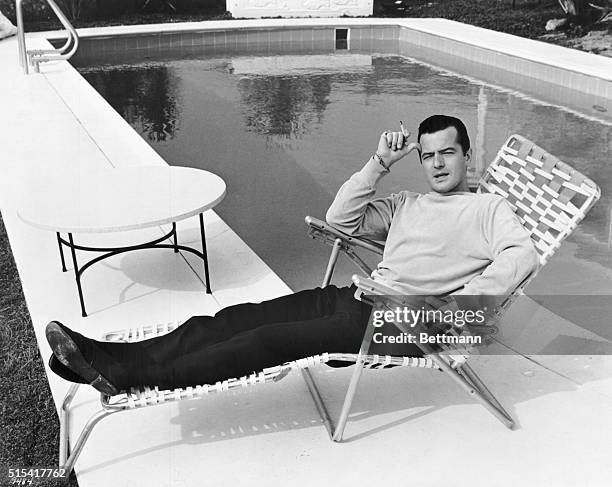 Actor Robert Goulet relaxing by a swimming pool in a promotional portrait for the 1964 comedy film Honeymoon Hotel.