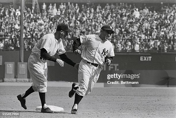 Third base coach Frank Crosetti gives Yogi Berra a congratulatory pat as latter rounds third after hitting two run homer in 4th frame of the 2nd...