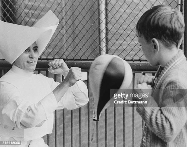 No Sissy Sister young boy finds where physical fitness is a popular aspect of program at Guardian Angel Settlement Association. A new punching bag...