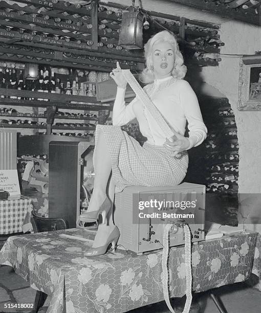 Actress Jayne Mansfield is thrilled as she holds the punched tape of a robotester, which made its press debut at Leone's Restaurant today. A...