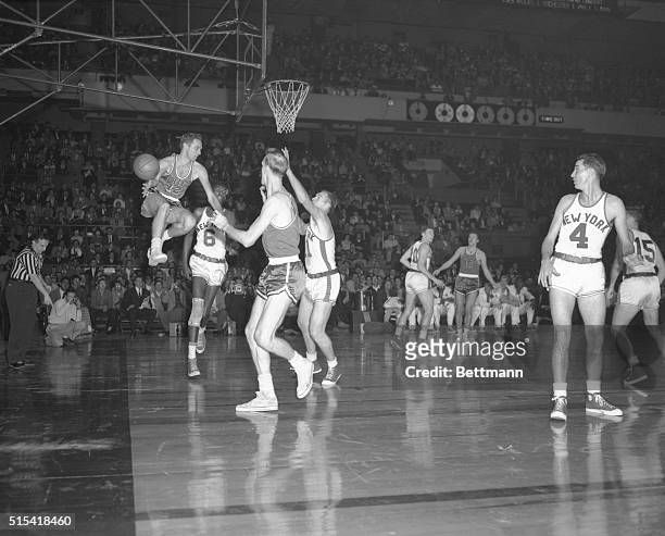 Walter Davis of the Philadelphia Warriors leaps high to grab the ball after Harry Gallatin of the Knicks missed a layup. Action was in the first...