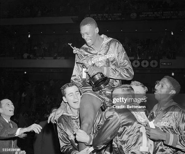 San Francisco teammates raise big Bill Russell on their shoulders in a spontaneous gesture of acclaim following tonight's triumph over the clans,...