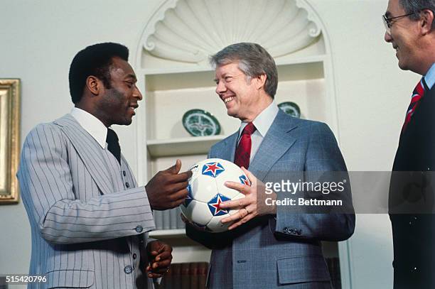 Brazilian soccer player Pele, of the New York Cosmos, gives a soccer ball to President Jimmy Carter during a White House visit.