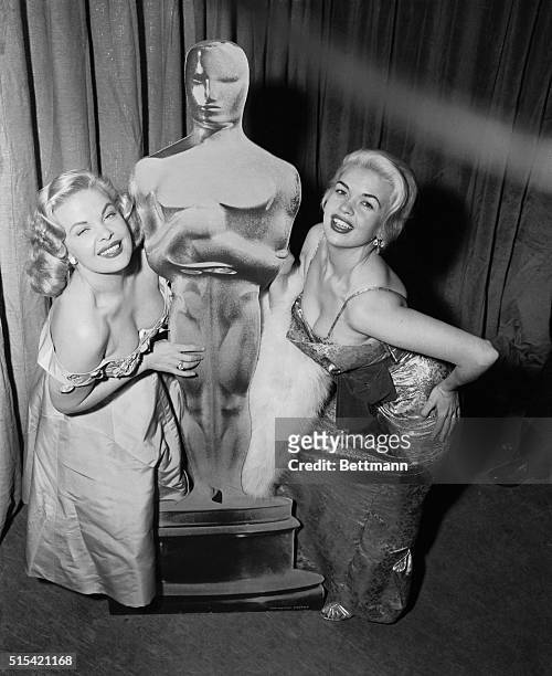 Actresses Cleo Moore , and Jayne Mansfield display their charms beside an "Oscar" at the Century Theater in New York tonight while waiting to hear...