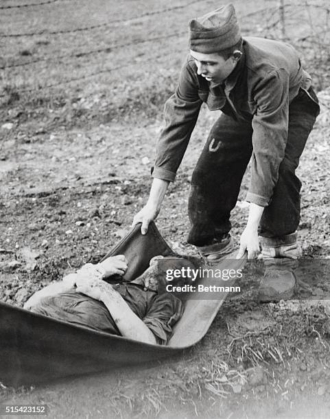 Prisoner who died in the former German prisoner-of-war camp at Sarreguemines, France, on the U.S. 3rd Army front, is being removed by one of his...