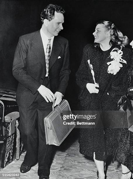 Hollywood, Calif.: Ingrid Bergman holding her "Oscar" is accompanied by her husband Dr. Peter Lindstrom, as they leave Hollywood's Grauman's Chinese...