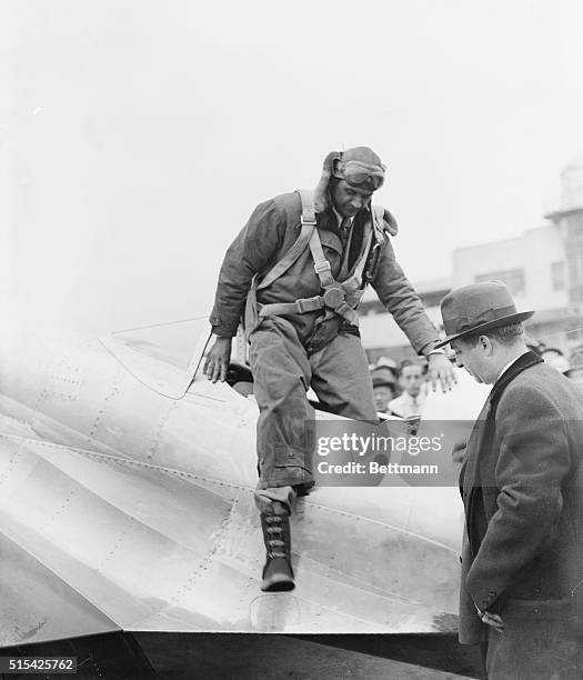 Howard Hughes, sportsman, pilot, and movie producer is shown alighting from his silver monoplane at Newark Airport after having shattered the...