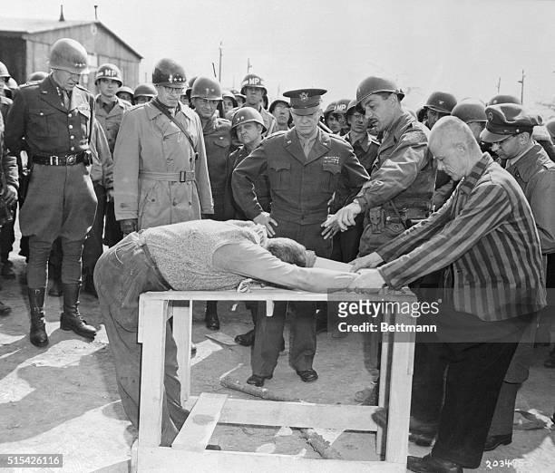 General Dwight D. Eisenhower looks on grimly as occupants of concentration camp at Gotha demonstrate how they were tortured by Nazi sadists operating...