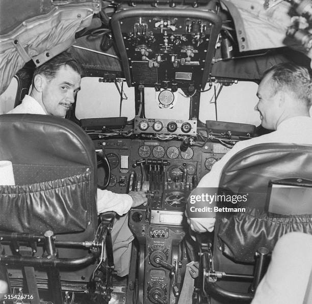 Howard Hughes and R.C. Loomis, in the cockpit of a TWA Constellation, demonstrate a new radar terrain clearance warning instrument.