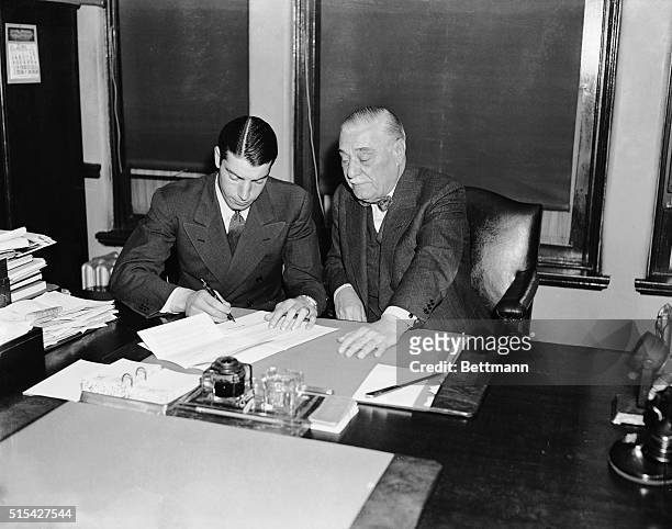Joe DiMaggio, noted slugger and preseason holdout from his berth with the New York Yankees, is pictured as he signed a new contract to play with the...