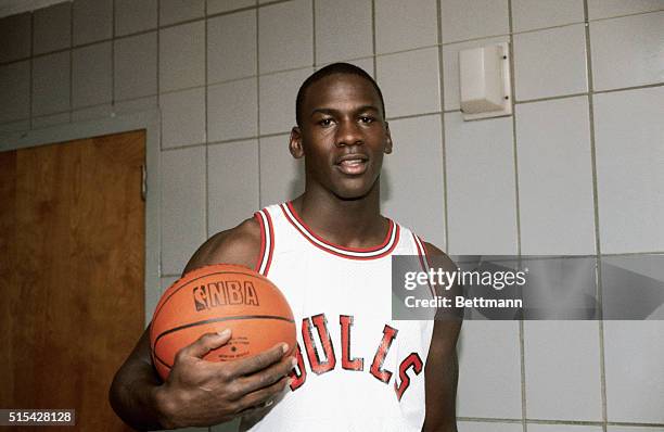 Michael Jordan, forward for the Chicago Bulls, holding a basketball in the locker room.