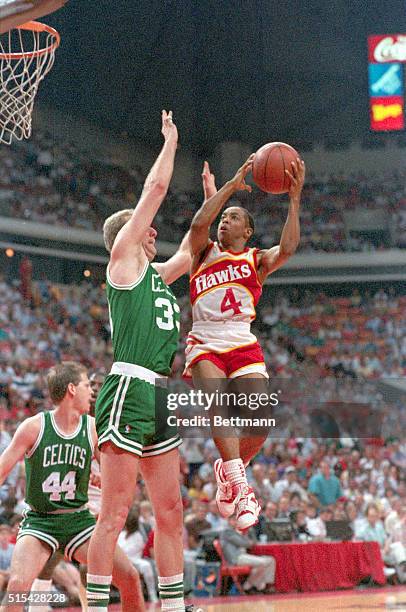 Atlanta; Hawks' smallest player, 5'7" Spud Webb goes up high for two points over Boston big man Larry Bird in 1st quarter action.