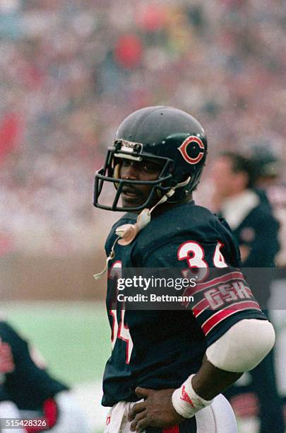 Walter Payton is shown standing on the field during a game with the New Orleans Saints. Waist-up photograph.