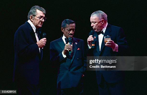 Rat Pack members Dean Martin, Sammy Davis, Jr., and Frank Sinatra sing together on stage during a concert tour.