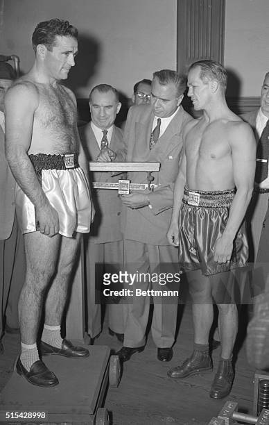Tony Zale, middleweight champ , and Marcel Cerdan weigh in at Jersey City as State Boxing Commissioner Abe Greene adjusts scale. Andy Niederreiter,...