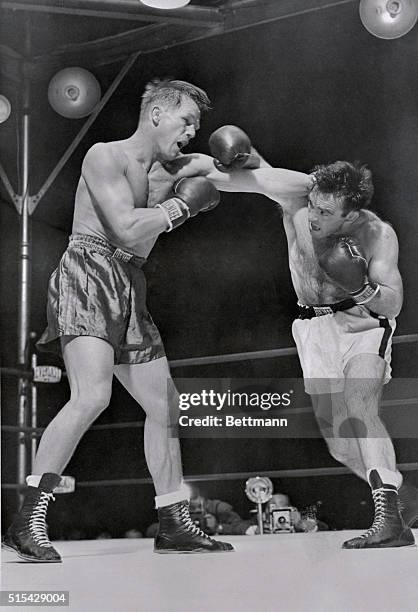 Tony Zale's famed left misses and elusive Marcel Cerdan prepares to counter with his own left as Zale tires in Jersey City. Cerdan won the crown in...