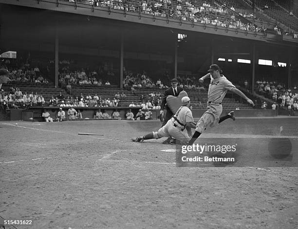 Hank Greenberg, hard-hitting left fielder for the Detroit Tigers, crosses home plate from third on first baseman Rudy York's left field fly to Bob...