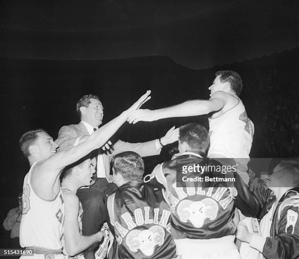 Jubilant North Carolina Tar Heel basketball players hoist Coach Frank McGuire and Joe Quigg on their shoulders after defeating Kansas, 54-53, in a...