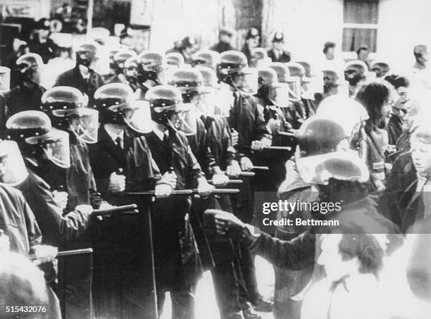 Police with batons drawn and wearing riot helmets confront anti-apartheid protesters outside the rugby ground where the touring South African...