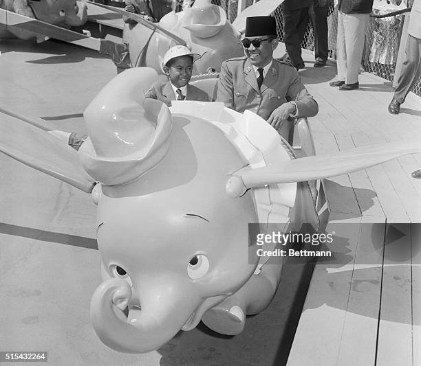 Anaheim, California- Dr. Achmed Sukarno, President of Indonesia, now touring the US, is shown with his son, Guntur riding behind "Dumbo," one of the...