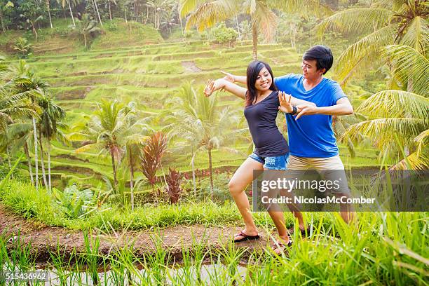 two young balinese people rehearsing dance in rice paddy - ubud rice fields stock pictures, royalty-free photos & images