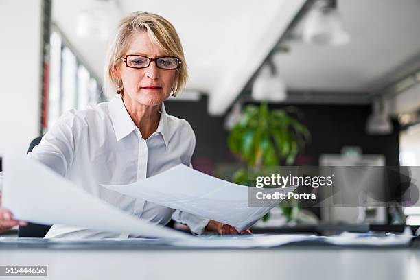 businesswoman examining documents at desk - draft bildbanksfoton och bilder