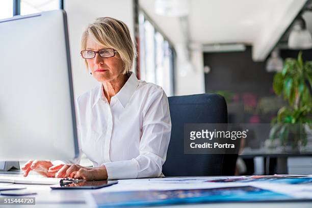 empresaria usando la computadora en escritorio de oficina - mujer escritorio fotografías e imágenes de stock