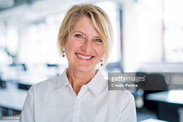 portrait of happy businesswoman in office - vrouw 50 jaar stockfoto's en -beelden