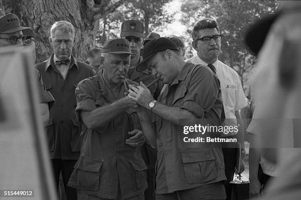 An Hoi Village, South Vietnam- Secretary of Defense Melvin Laird and General Creighton Abrams light each other's cigars as they listen to a briefing...