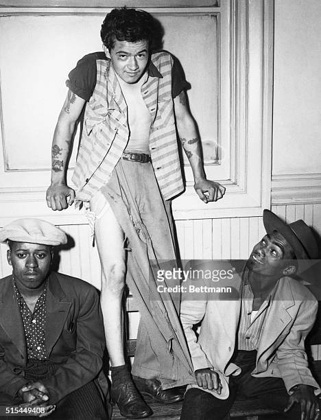 Paul Acevedo stands in his tattered clothing, flanked by two men in zoot suits following the "Battle of Gangland" in Los Angeles, California. Since...
