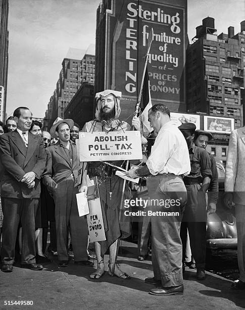 New York, NY-: Blind Louis Hardin, who carries an "Abolish Poll Tax" sign, startles New York citizens with his odd costume. He also sells a booklet...