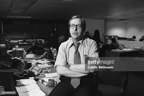 Nightly News anchorman John Chancellor sits on a desk in the NBC newsroom.